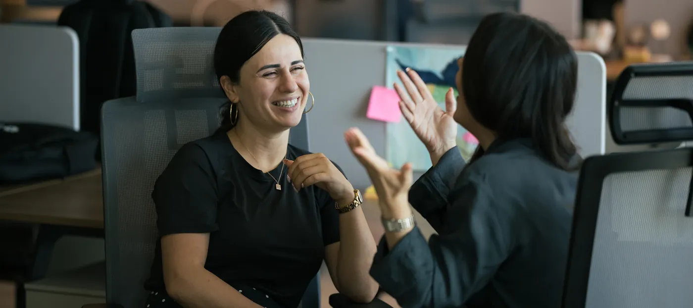 Two colleagues laughing while handling customer chats