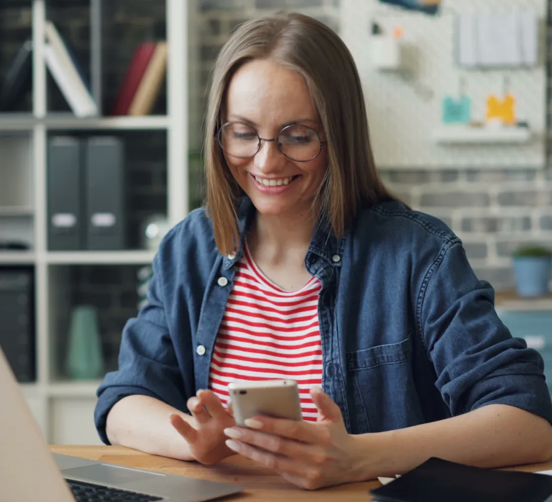 Woman replying to a message on her phone at her desk